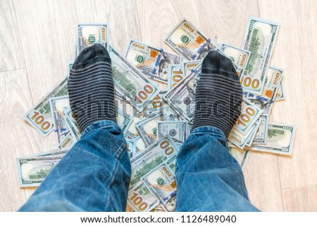 the man with stripped socks standing on the dollars