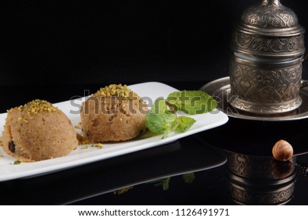 Turkish dessert irmik halva of semolina with syrup on a plate next to a cup of coffee. Dark background, menu shot, food photo