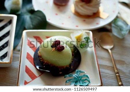 Pistachio mousse cake in the fishing Culinary art. On striped graphic saucers