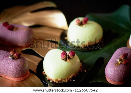 Moscovie cakes purple and lemon yellow. Pistachio and fruit. Culinary art. Gold leaf monstera