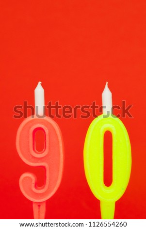 Colorful burning birthday candle  on red background