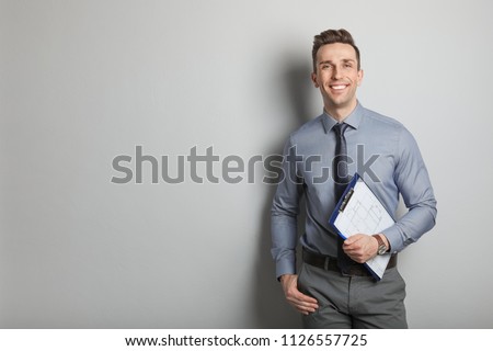 Male real estate agent with clipboard on grey background Royalty-Free Stock Photo #1126557725
