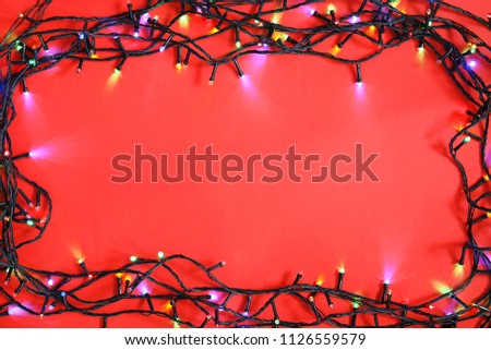Glowing Christmas lights on color background, top view