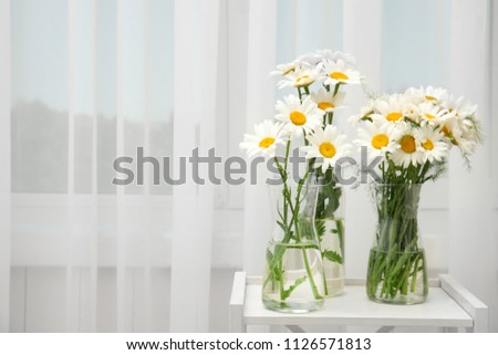 Vases with beautiful chamomile flowers on table