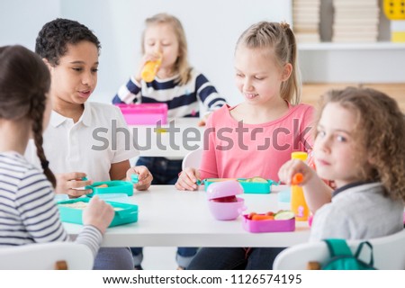 Multicultural group of kids eating lunch at school