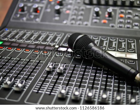 microphone rests on an audio mixer controller in the control room, Sound mixer control for live music and studio equipment, Quality audio system for professionals, music equipment concept Royalty-Free Stock Photo #1126586186
