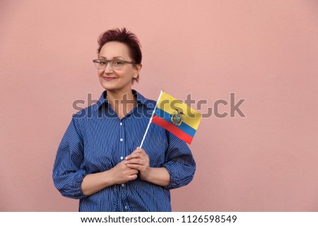 Ecuador flag. Woman holding Ecuadorian flag. Nice portrait of middle aged lady 40 50 years old with a national flag over pink wall background outdoor.