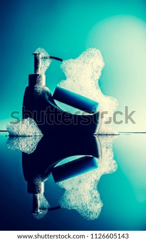 A sponge and foam on a tiny bath with reflection on a blue background. Vintage, grunge old retro style photo.