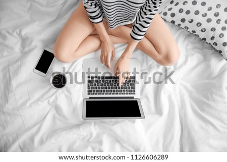 Female blogger with laptop and cup of coffee on bed, top view