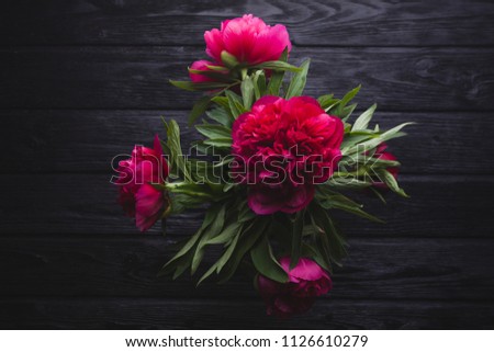 bouquet of red peonies on a black wooden background