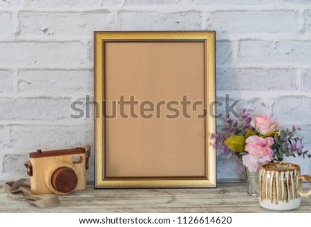 Vertical template frame mockup modern art on the wooden table with rustic vintage brick wall, decorated with colorful flower in small tin can, coffee cup, and wooden camera