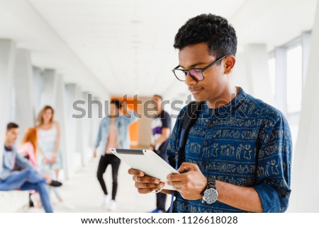 A young Indian student at the university is standing with a tablet. The photo illustrates education, schooling, college or university.