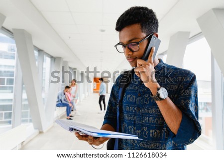 A young Indian student at the university is talking on the phone. The photo illustrates education, schooling, college or university.