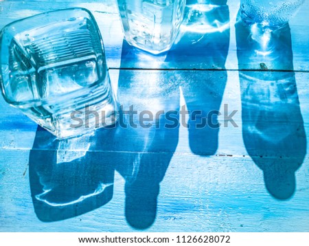 Water glare from the bright day sun on a blue wooden background. Transparent water bottles. Freshness, thirst, summer, heat