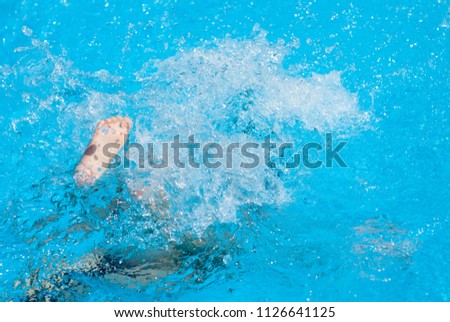 foot of diving drowning child on water surface of summer swimming pool
