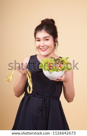 Healthy  Asian woman with measuring tape and salad  on beige background