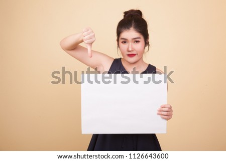 Young Asian woman show thumbs down with white blank sign  on beige background