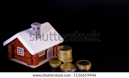Mortgage loan and real estate tax macro financial Concept, Scandinavian house model and pile of coins money on dark black background.