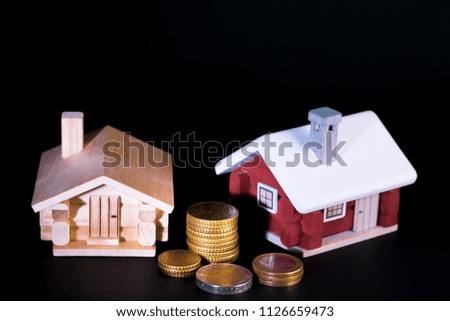 Mortgage loan and real estate tax macro financial Concept, Scandinavian house model and pile of coins money on dark black background.