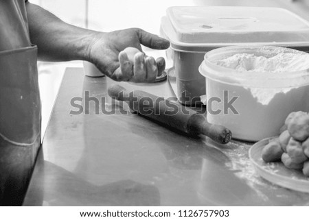Male hand kneading and roll out the dough to prepare making Indian food chapati or  flatbread using rolling pin and flour.