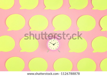 Bright, empty yellow stickers on a pink background. In the center is a small pink alarm clock. Beautiful bright picture from the top, mock up.
