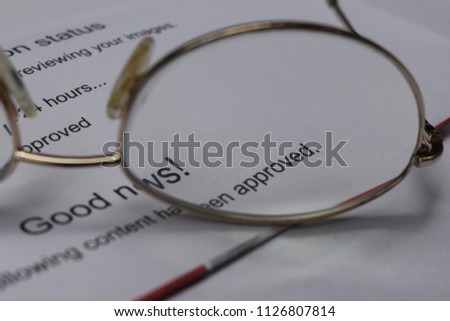 Good news. Your content has been approved. Word Approved magnified by glasses lens. Printout of email from a stock photo agency