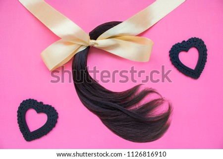 Cut off ponytail hair with black hearts, pink background