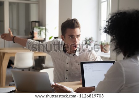 Mad male worker yelling at female colleague asking her to leave office, multiracial coworkers disputing during business negotiations, employees cannot reach agreement, blaming for mistake or crisis Royalty-Free Stock Photo #1126819703