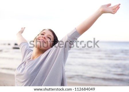 Woman stretching her arms to enjoy the fresh air of the sea Royalty-Free Stock Photo #112684049