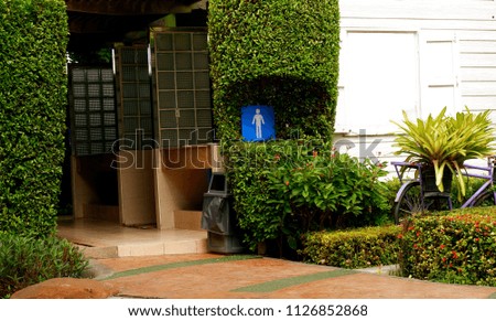 The entrance of men's restroom with blue sign on natural green background