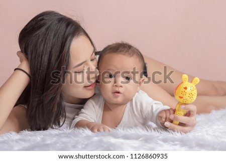 Family portrait of mom and baby in white clothes on the bed.