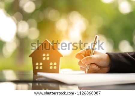 Young woman sign banking Loan Contract for buying a new land house from real estate agent, instalment payment by monthly basis as planning for long term contract. Dreaming to become owner residence. Royalty-Free Stock Photo #1126868087