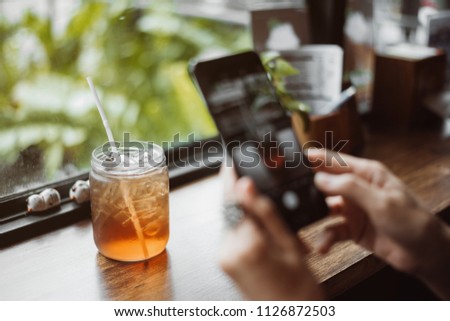 woman using a mobile phone capturing photos of ice tea for her blog.