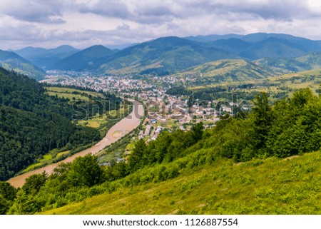 A city spread out in a mountain valley on the banks of a fast river surrounded by a delightful nature