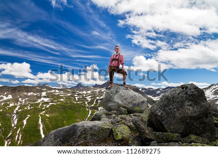 Young mountain explorer in traditional clothing in the Swiss Alps on top of the mountains