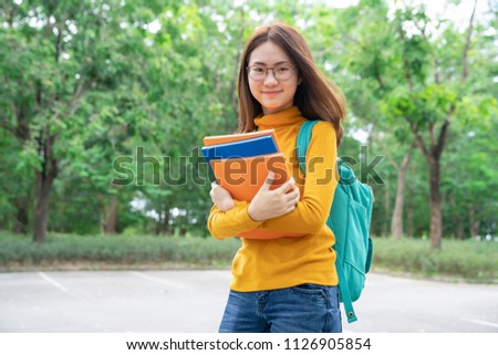 Summer holidays, education, campus and teenage concept - smiling female student in black eyeglasses with book