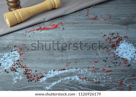 wooden background with scattered spices on it. Top view on with pepper salt and tomato