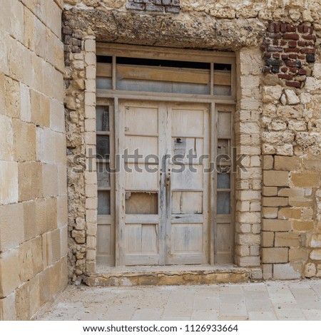 Facade of old abandoned weathered wooden door and stone bricks wall