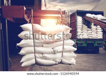 Forklift handling white sugar bags from warehouse for stuffing into container for export, vintage color. Royalty-Free Stock Photo #1126940594