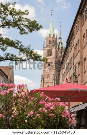 Vertical view of downtown Nuremberg, Germany, with outdoor cafe, flowers and St. Lawrence church in background on a summer day