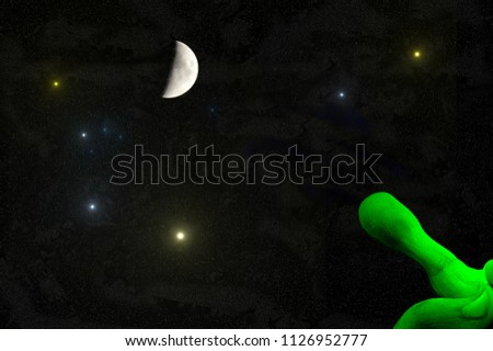 universe - green alien hand with outstretched finger pointing to the moon and the stars