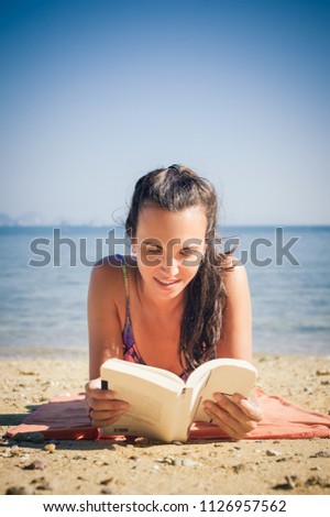 Woman reading book while enjoying the sunshine at the beach. Koh Hong Island, Thailand