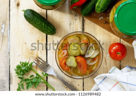 Pickled cucumber salad with tomatoes on the kitchen wooden background. Homemade pickle. Top view flat lay background, copy space.