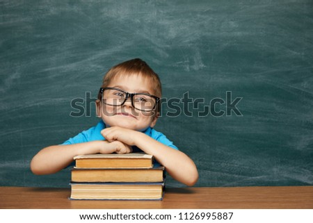Back to school concept. School child (boy) in classroom. Funny kid against green chalkboard. Idea and creativity concept. Copyspace on chalkboard background