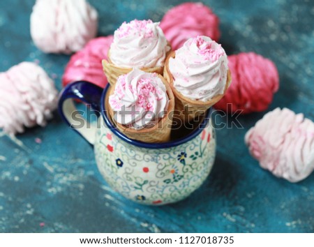 Homemade pink marshmallow with berries in waffle cones on a dark background. Selective focus.