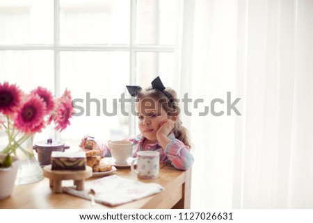 A little girl at the table is eating breakfast by the window. Good morning. Copy space.