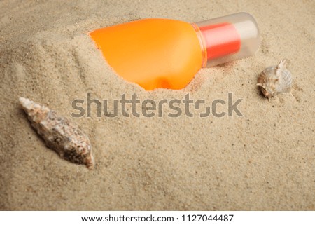 Protective suntan cream lies in the beach sand.