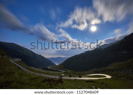 Landscape with mountains and an empty highway at night, under starry sky