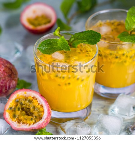 The passion fruit cocktail with mint and ice cubes in glass on the table