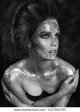 girl with gold face painting. professional makeup. studio close up portrait of beautiful girl with body art